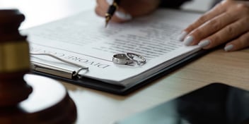A lawyer completing a divorce contract with wedding rings on table