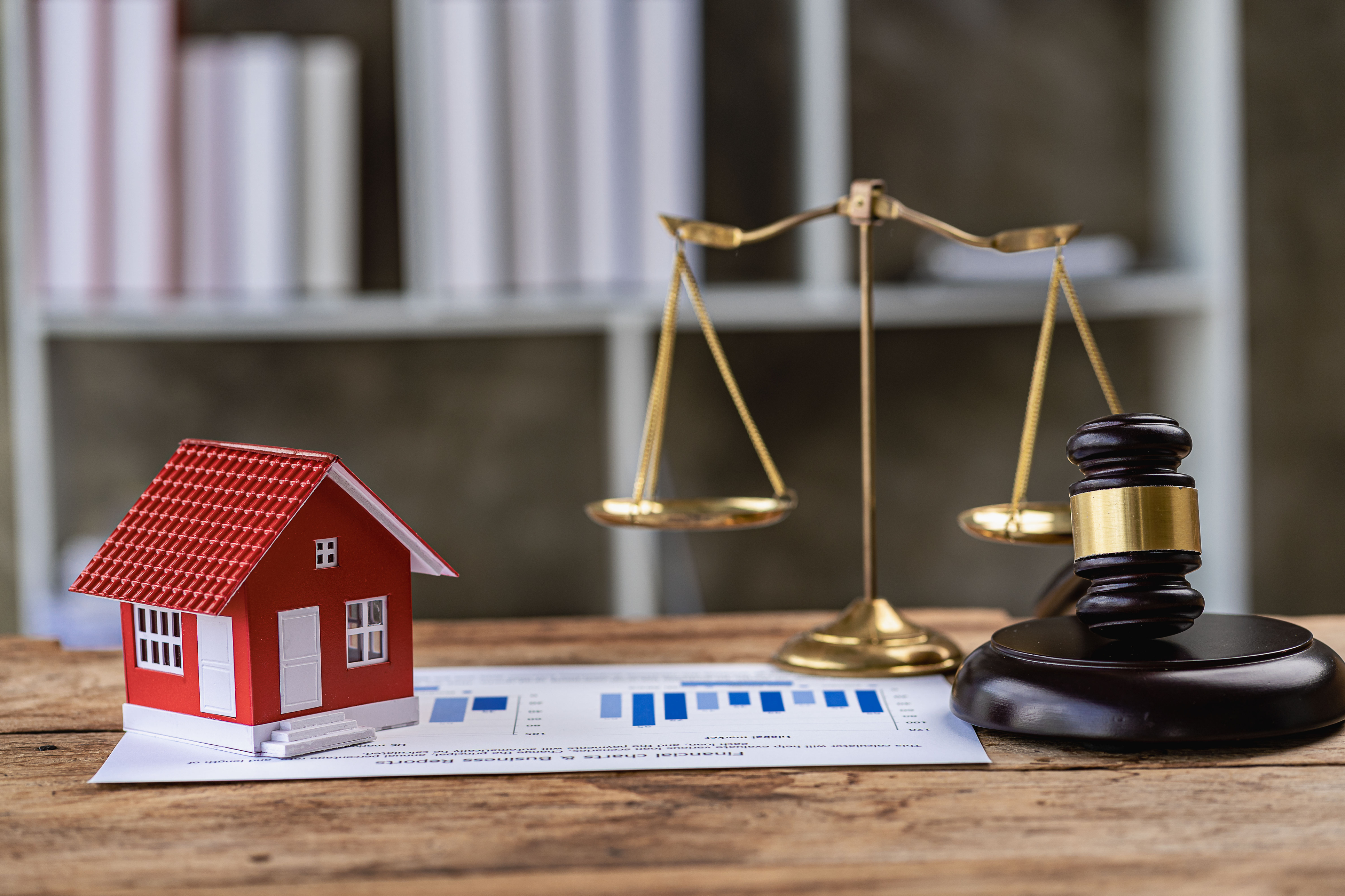A house, gavel, and balance on a desk. 