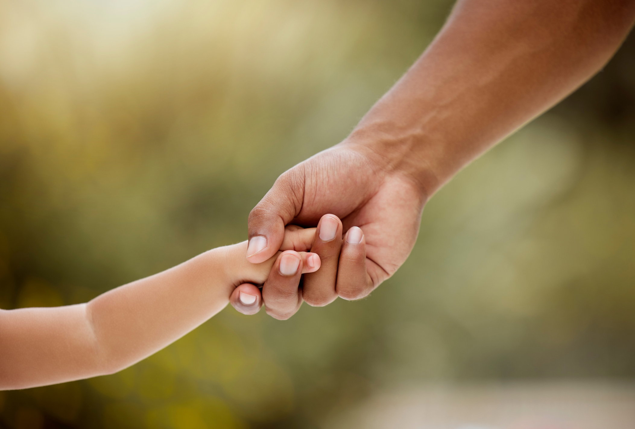 Hand of parent and child holding hands outside