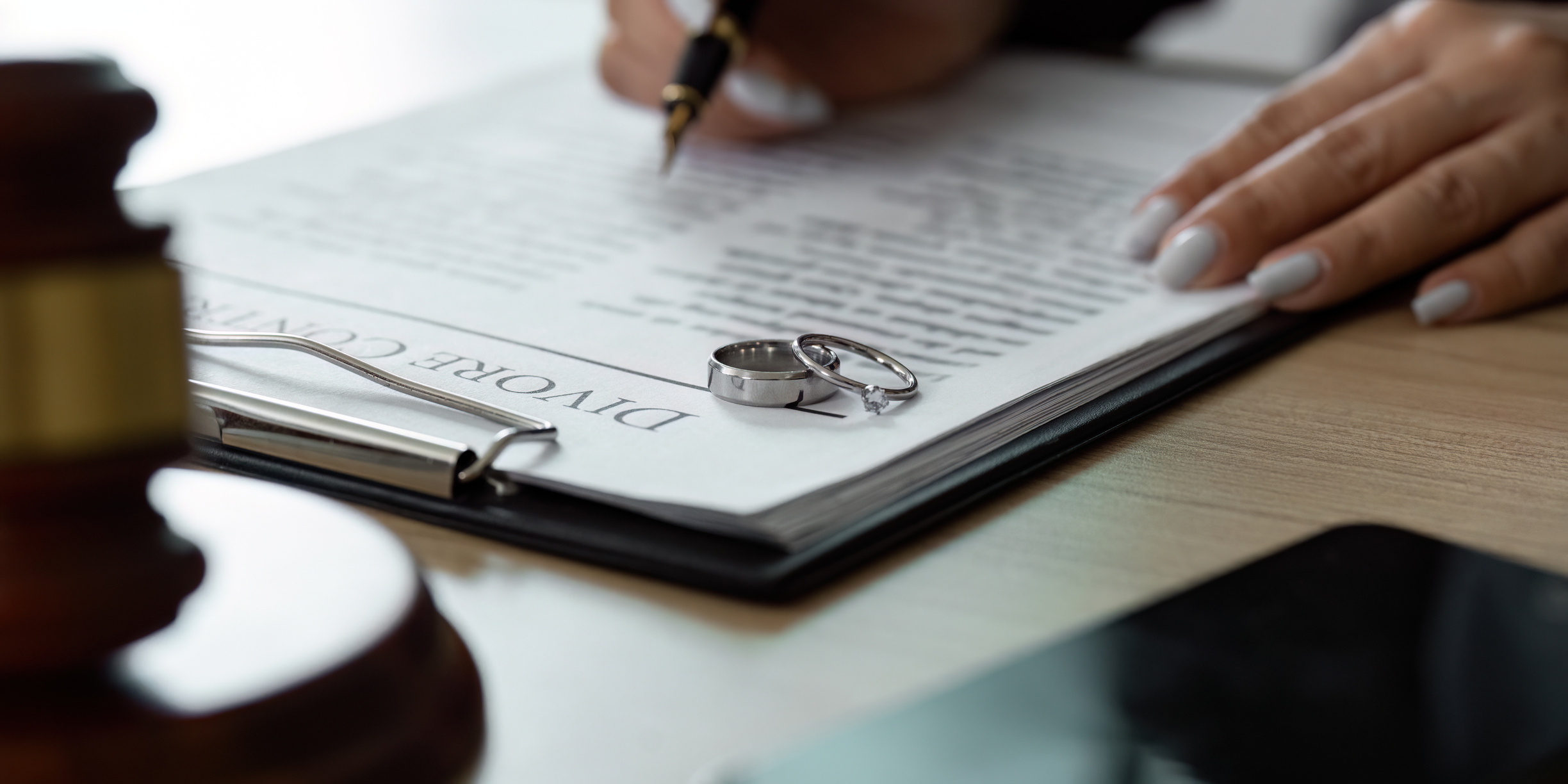 A lawyer completing a divorce contract with wedding rings on table